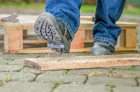 Worker with safety boots steps on a nail